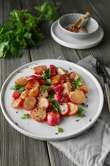 Beautiful roasted radishes served with parsley and sesame seeds in a plate on wooden rustic background.
