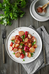 Beautiful roasted radishes served with parsley and sesame seeds in a plate on wooden rustic background.