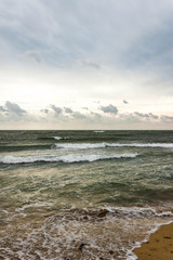 Blue and green waves with white foam on sandy beach. Black Sea, Evpatoria, Crimea, Russia. Travel, wacation concept. Text copy space.