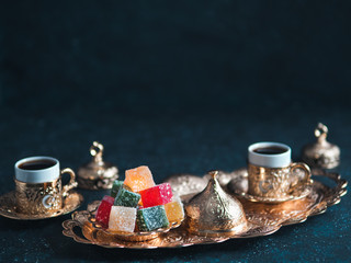 Turkish coffee with delight and traditional copper serving set on dark background. Assorted...