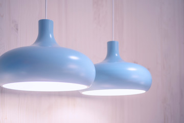 blue lamp hanging on the white cable on wall background