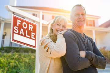 Attractive Middle-aged Couple In Front House and For Sale Real Estate Sign