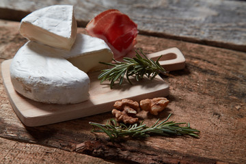 Delicious assorted appetizer with cheese and prosciutto and walnuts on wood table