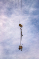 Fototapeta na wymiar A hook of a crane with load at the blue sky with clouds as a background. Vertical view