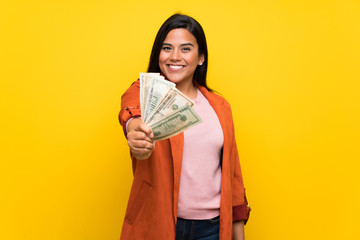 Young Colombian girl over yellow wall taking a lot of money