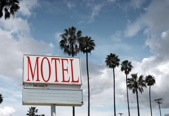 aged and worn motel sign with palm trees