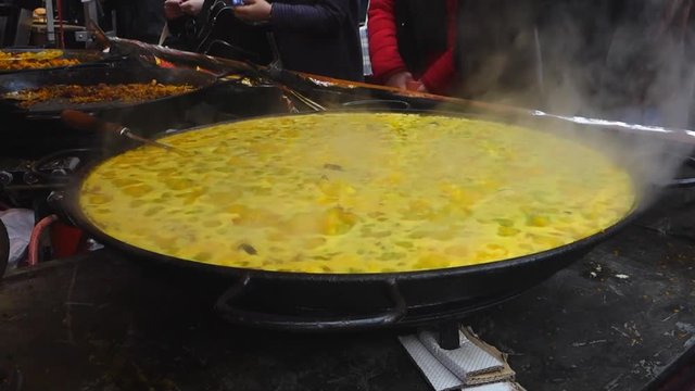 A large pan of paella cooking at a market stall in Portobello Road, London