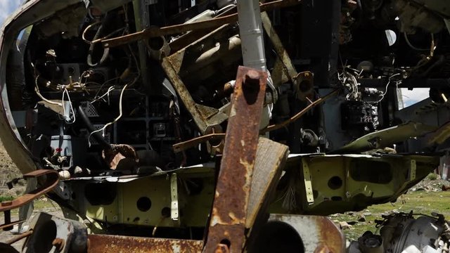 A hand held, tilting, extreme close up shot of a metal carcass of an airplane, under the cloudy, blue sky.