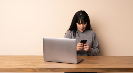 Young woman working with her laptop surprised and sending a message