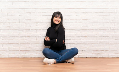 Woman sitting on the floor with arms crossed and happy