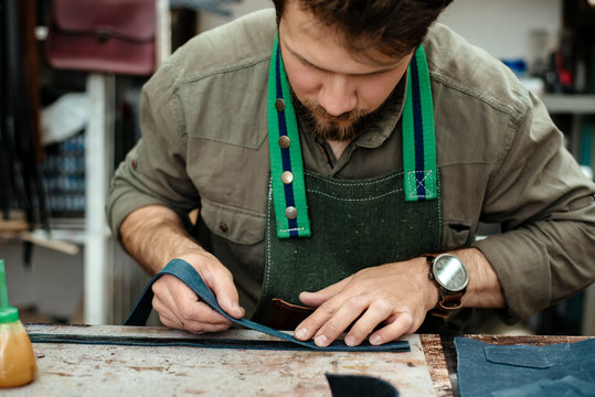 A master glues parts for future products made of genuine leather