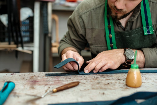 A master glues parts for future products made of genuine leather