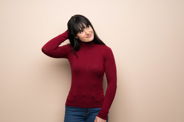 Young woman with red turtleneck thinking an idea while scratching head