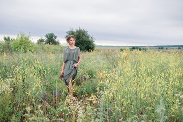 Fototapeta premium beautiful young girl in a summer dress in a field on a background of green grass