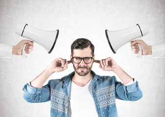Man covering ears, two loudspeakers