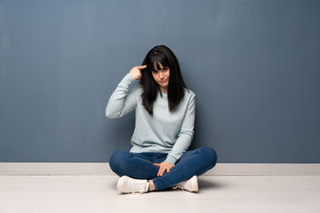 Woman sitting on the floor making the gesture of madness putting finger on the head