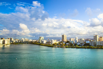 View of Condado area of San Juan Puerto Rico with bay and buildings on a day with clouds and sun.