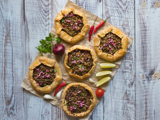 Open meat pies on a black background. Top view.