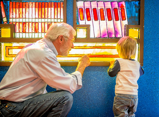 Grandfather Teaches Grandson to Read at Library