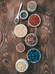 Obraz na płótnie Canvas Various superfoods in small bowl on wooden table.Selection super food.Superfood as blueberry, chia, raw cocoa bean, goji, hemp seeds, quinoa, brown rice. Copy space.Top view or flat lay.Vertical