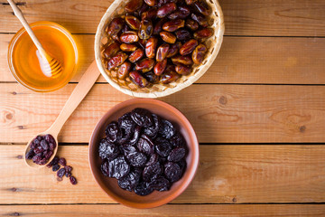 Dried dates, prunes and honey on wooden background. Holy month of Ramadan, concept. Righteous Muslim lifestyle. Starvation. Dried fruits: dates, prunes and raisins on wooden boards