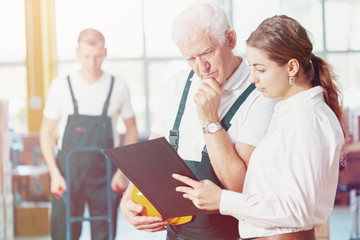 Senior plant manager in emerald green uniform and office worker checking documents together