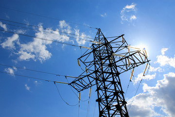 Silhouette of power lines in the solar flare on a background of blue sky