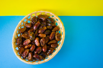 Dried dates on a yellow blue background. Holy month of Ramadan, concept. Righteous Muslim lifestyle. Starvation. Dates in a wooden basket in the style of minimalism