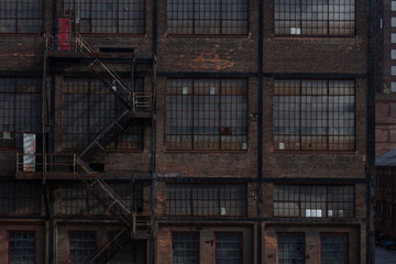 Brick exterior of an industrial building with banks of windows and fire escape, horizontal aspect