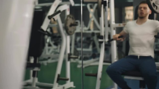 Man with a sports figure doing exercise on simulator in the gym.