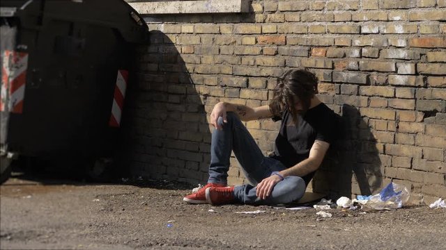 portrait of young man done drug alone sitting in the street.Drug,addiction,degradation