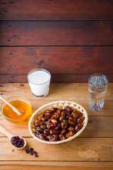 Dried dates, milk and honey on wooden background. Holy month of Ramadan, concept. Righteous Muslim lifestyle. Starvation. Dates in a wooden basket and raisins in the style of minimalism