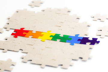 LGBT pride flag, built from a puzzle, among gray puzzles, short focus, on a white background, side...