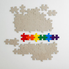 equality concept: LGBT pride flag built from a puzzle, among gray puzzles short focus, top view