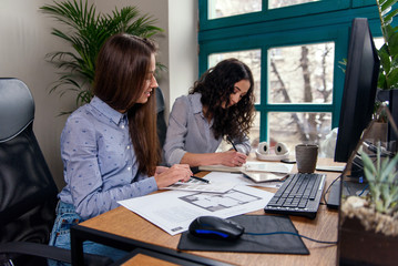 Handsome women architects in blue shirts working with color palatte to choose design and colors on the office background.