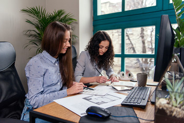Handsome women architects in blue shirts working with color palatte to choose design and colors on the office background.