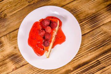 White plate with cheesecake New York and raspberries on wooden table. Top view