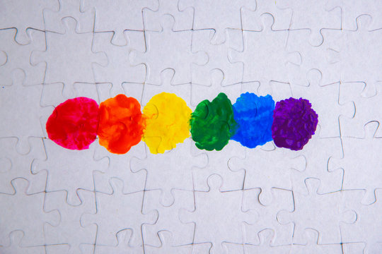 Place of LGBT people in the public structure: puzzle with the coloring of the rainbow flag against a white mosaic, top view - Powered by Adobe