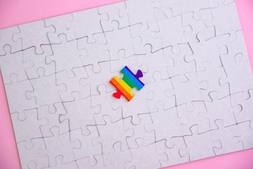 Place of LGBT people in the public structure: puzzle with the coloring of the rainbow flag against a white mosaic, top view