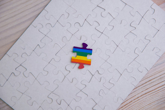 Place of LGBT people in the public structure: puzzle with the coloring of the rainbow flag against a white mosaic, front view