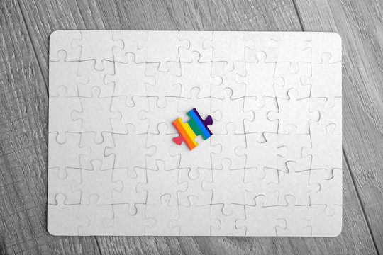 Place of LGBT people in the public structure: puzzle with the coloring of the rainbow flag against a white mosaic, top view