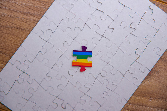 Place of LGBT people in the public structure: puzzle with the coloring of the rainbow flag against a white mosaic, front view
