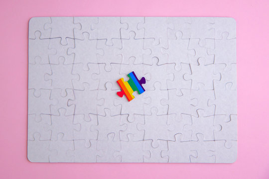 Place of LGBT people in the public structure: puzzle with the coloring of the rainbow flag against a white mosaic, top view