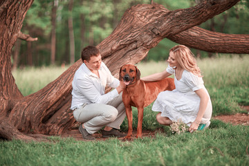 young family with their pet near the old spreading tree.