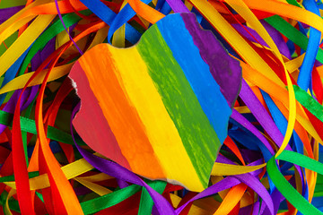Concept - oppression of freedom of the LGBT community: a burned and torn rainbow heart lies on a pile of rainbow ribbons