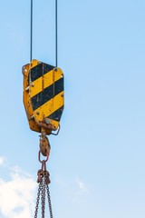 building construction: crane hook, chain and cables against the blue sky