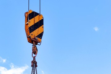 building construction: crane hook, chain and cables against the blue sky