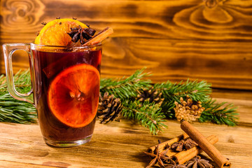 Cup of mulled wine with cinnamon and fir tree branches on wooden table