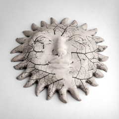 Fototapeta premium travel artifacts: antique ceramic sun with prominences, on a light background, short focus