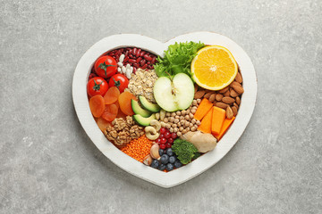 Heart shaped tray with healthy products on grey background, top view
